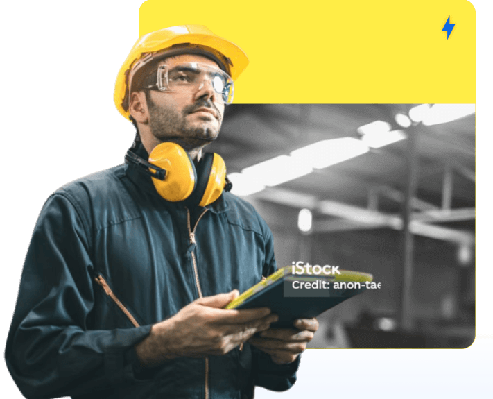 A man in a yellow hardhat holding a tablet.