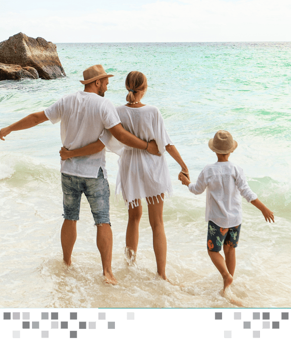 A family holding hands on the beach standing in the waves.